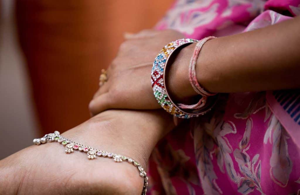 Close up of Indian woman's pendant anklet on right ankle and ethnic design bangles on left wrist