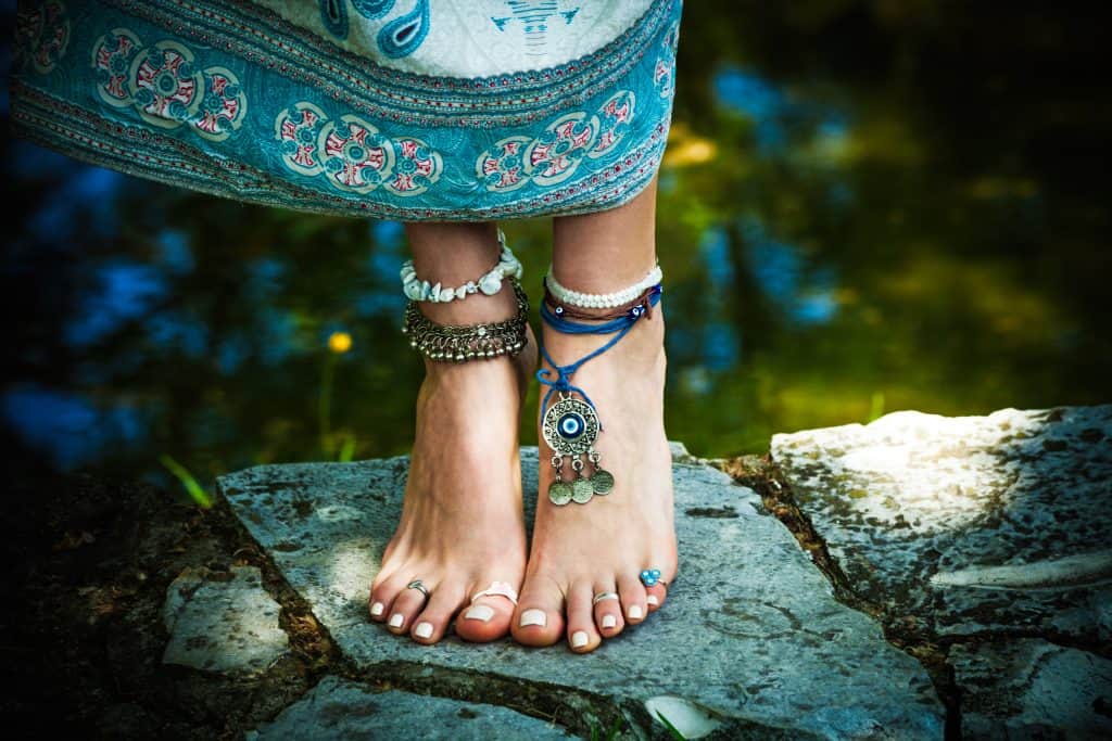 Woman wearing ethnic design beaded and pendant anklets on both ankles