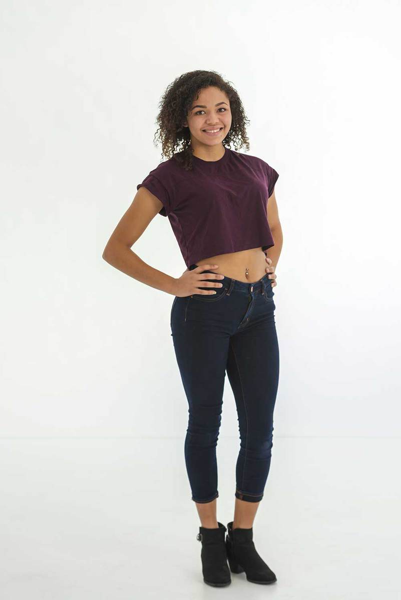 Young woman in crop top and jeans posing against a white background