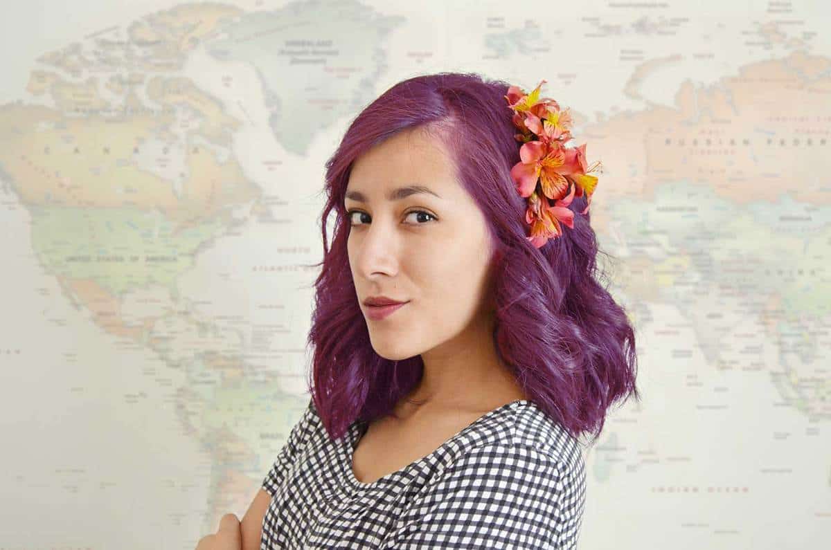 Young woman with pink-purple hair with world map as a background