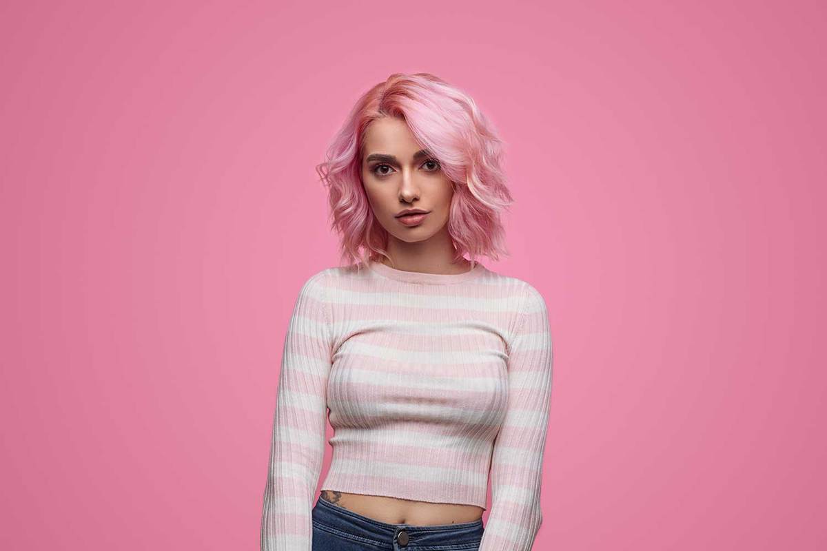 Charming slim woman with wavy pink dyed hairstyle wearing striped shirt