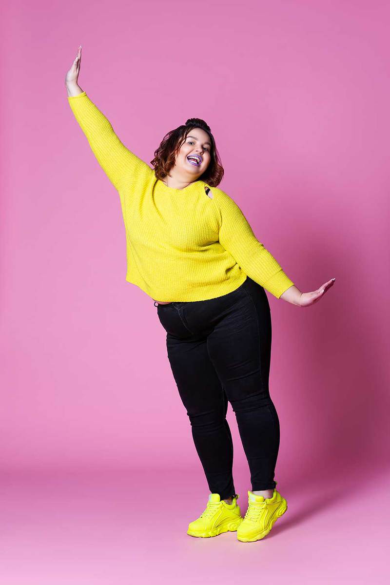 Cheerful plus size model in casual clothes, black jeans and yellow shoes