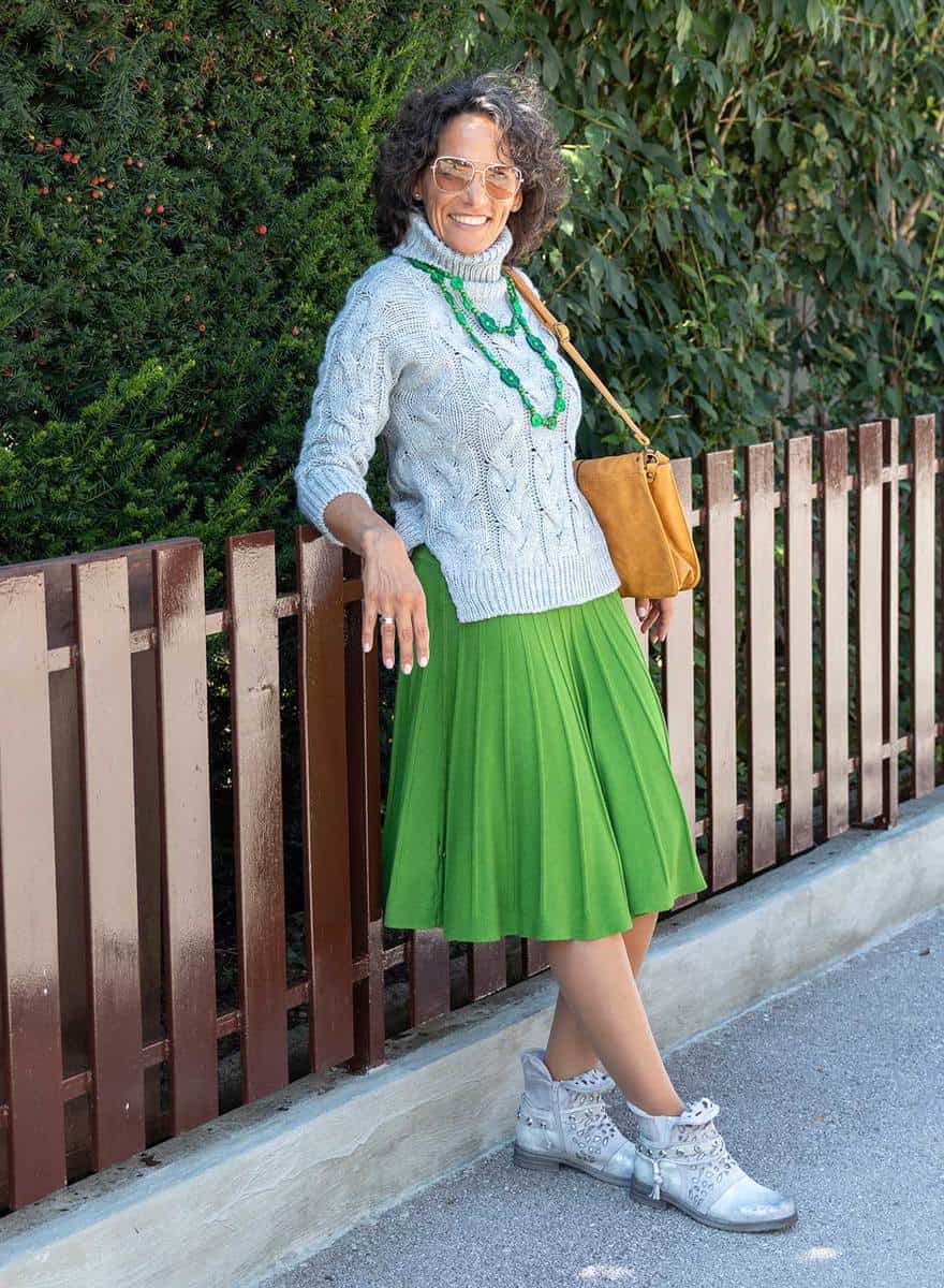 Mature woman in green wool skirt, knitted sweater and grey shoes with yellow shoulder bag