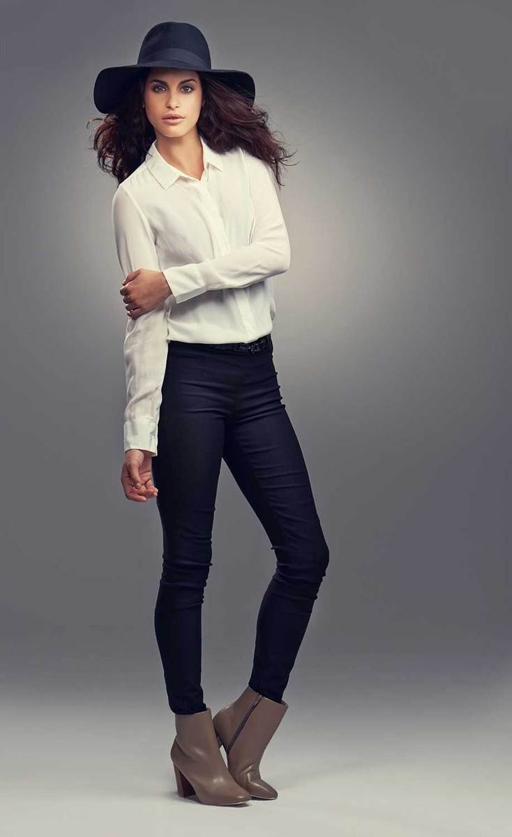 Studio shot of a stylish and beautiful young woman wearing skin tight jeans and grey heels