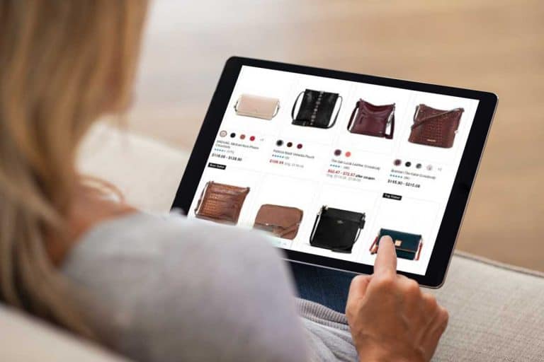 Blonde woman shopping and checking handbags online using a tablet