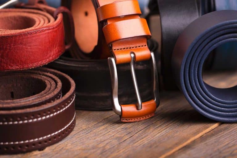 Collection of leather belts on a wooden table, Does A Leather Belt Stretch? [And What You Can Do About That]