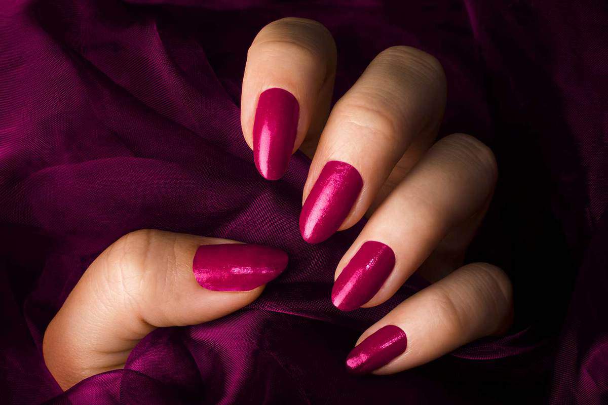 Женская рука с розовыми ногтями держит розовую ткань