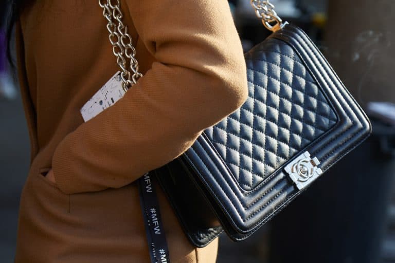 A woman walking on the streets on Milan while wearing her Chanel CC bag, How Much Does A Chanel Handbag Cost?
