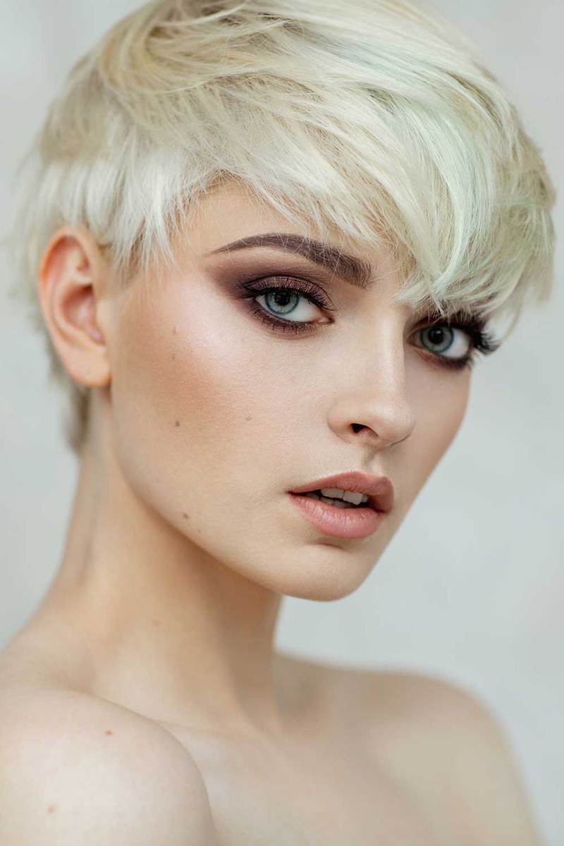 Beautiful blonde woman with short hair and evening make-up looking at camera