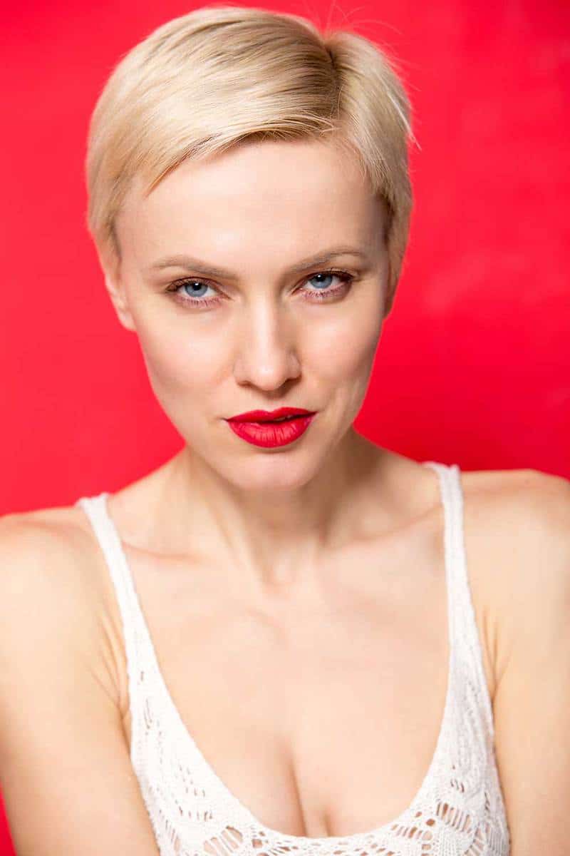 Beautiful blonde woman with short haircut against red wall