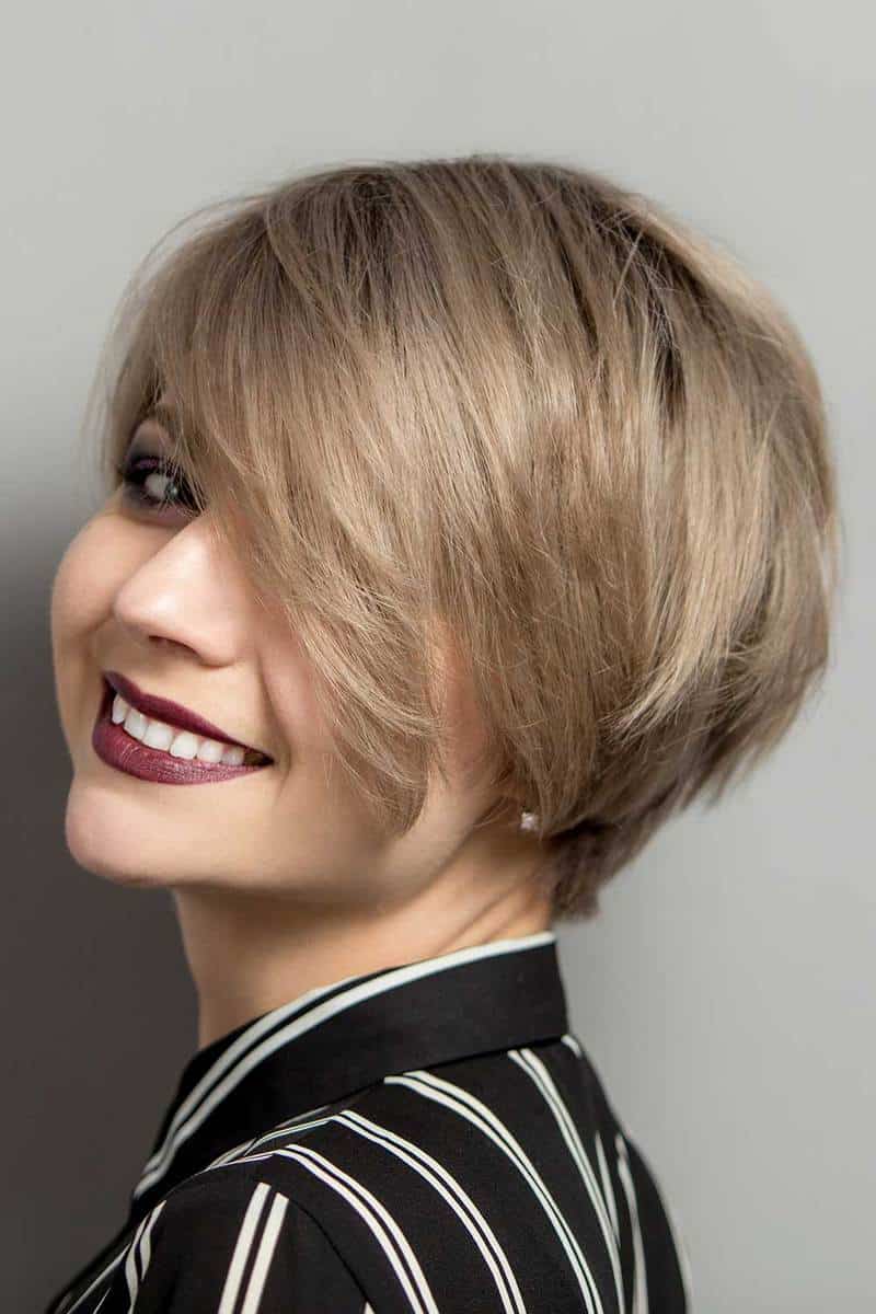 Beautiful young woman with short hair smiling over gray background