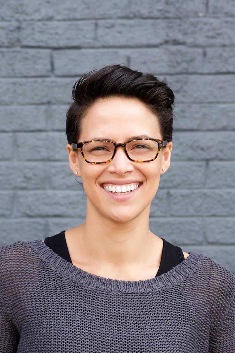 Close up portrait of an attractive young woman smiling with short hair and glasses on