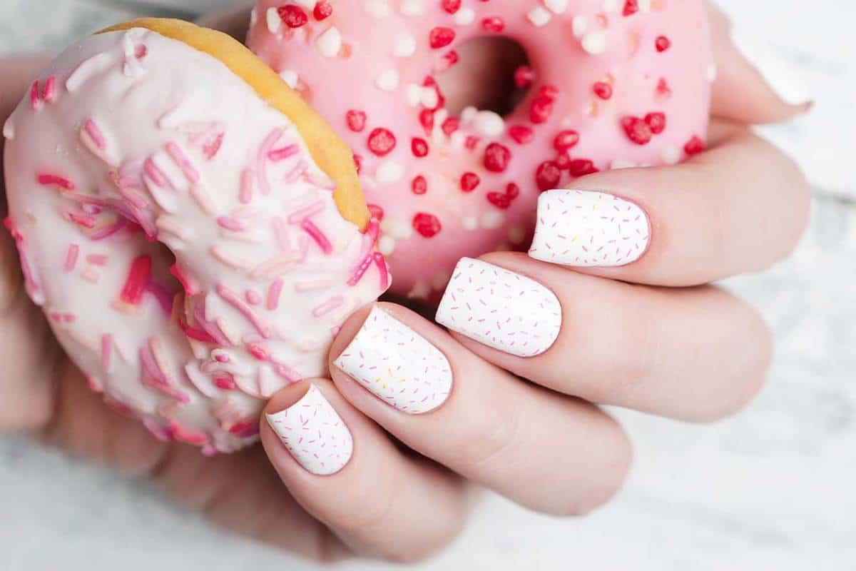White manicure with pink sprinkle on donuts pattern