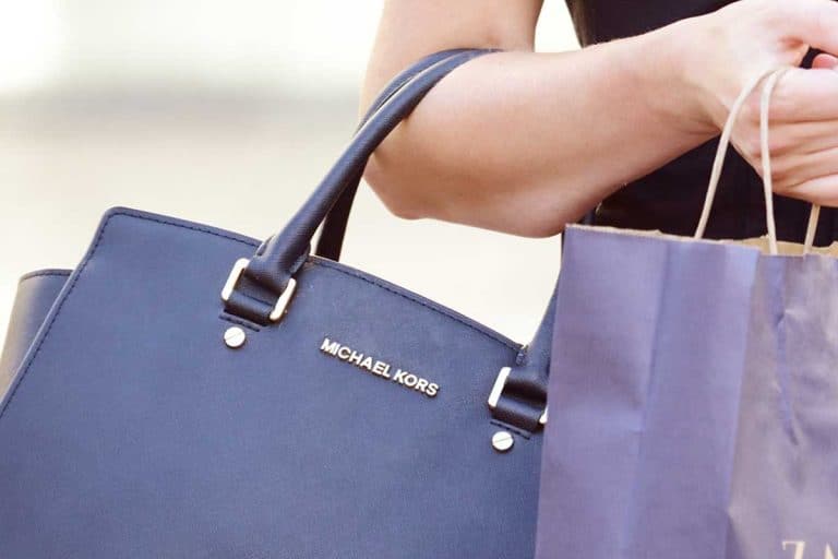 Woman shopping with blue Michael Kors handbag, Top 10 Handbag Brands Every Fashion Fan Should Know