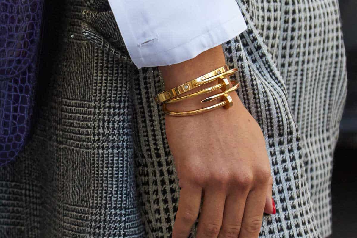 Woman with blue leather bag and golden Cartier bracelets, How Much Do Cartier Bracelets Cost?