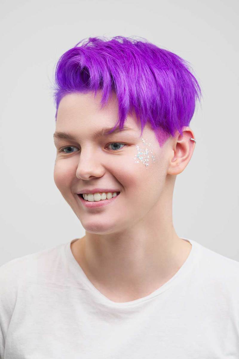 Молодая привлекательная женщина с фиолетовой стрижкой пикси в белой футболке