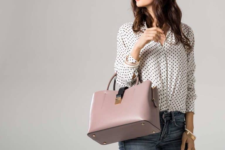 Young glamour woman wearing polka dot shirt and jeans posing with pink handbag during job interview, Should You Bring A Handbag To An Interview?