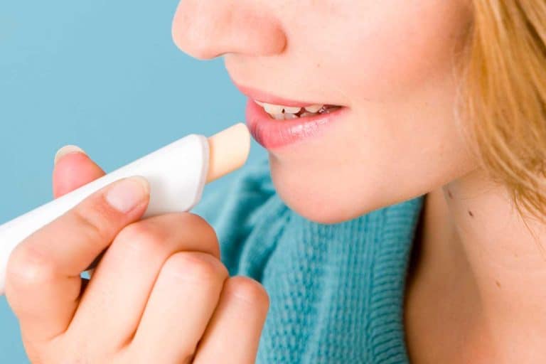 A woman putting chap protection lip balm, How Often Should You Apply Lip Balm?