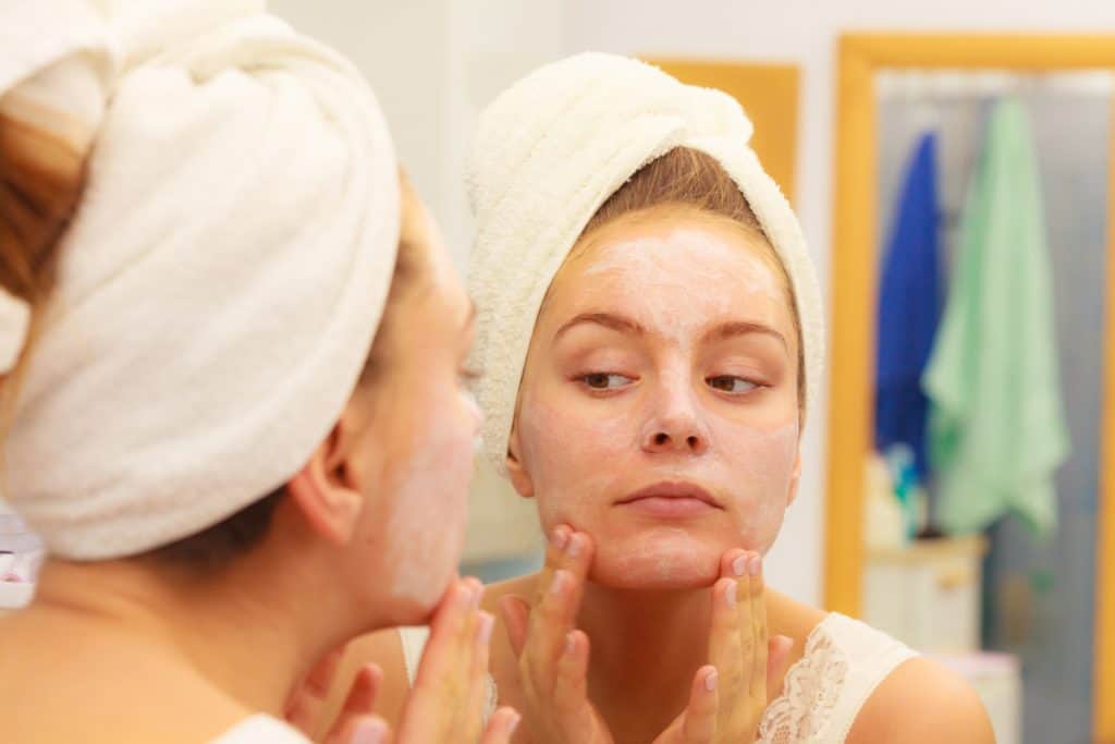 A woman putting on cold cream on her face