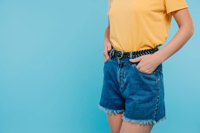 A woman wearing a yellow top and denim shorts with a belt buckle, 19 Types of Belt Buckles Every Fashion Fan Should Know