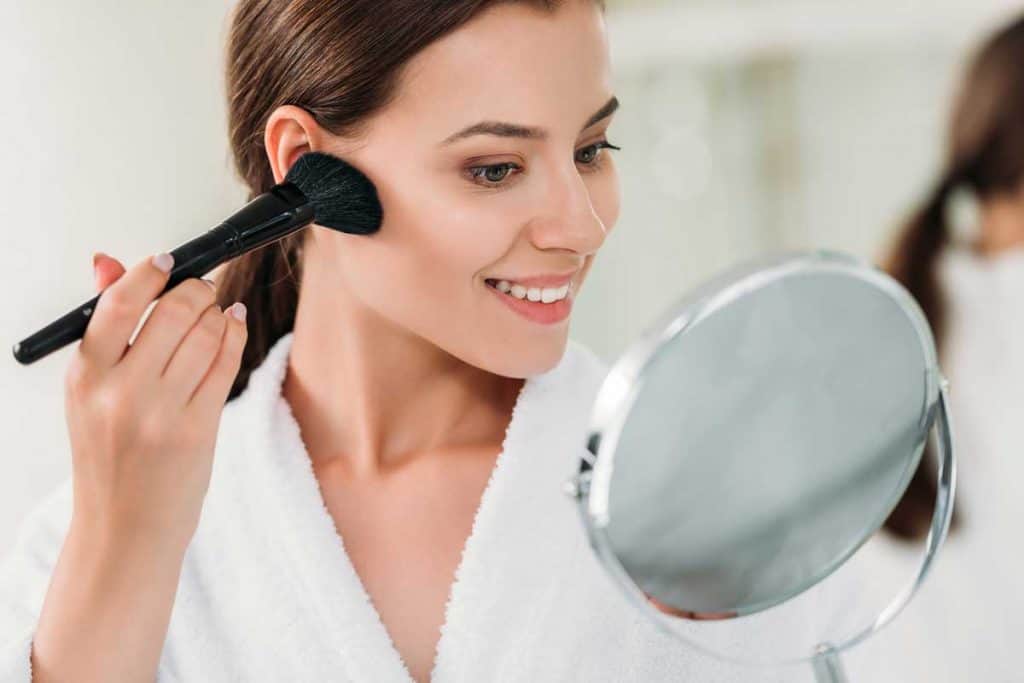 Beautiful smiling brunette girl in bathrobe applying powder bronzer with brush, My Bronzer Always Looks Patchy - What To Do?