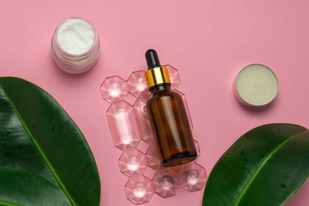 Cream jar, candles and glycolic acid bottle on a pink background skin and body care concept, Does Glycolic Acid Expire? Here's What You Need to Know