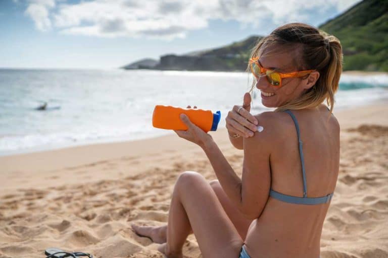 Young woman on beach applying sunscreen on her face, protection on skin and sunbathing tan concept, Do You Use Sunscreen Before Or After Moisturizer?