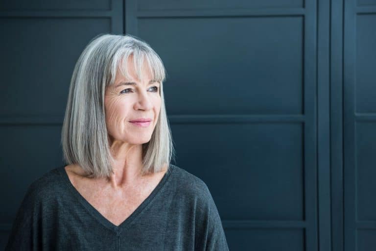 An elderly woman in a gray shirt standing on a black door with a bob hair cut, 25 Awesome Bob Hairstyles for Women Over 60