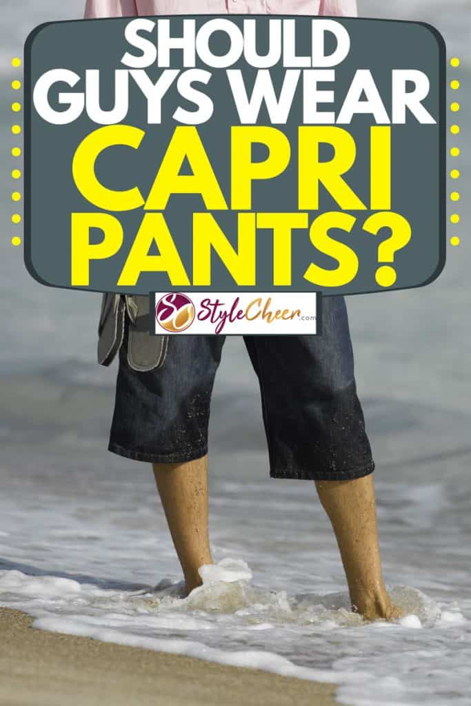 Man wearing a white top and semi wet Capri pants while standing on the shoreline, Should Guys Wear Capri Pants?