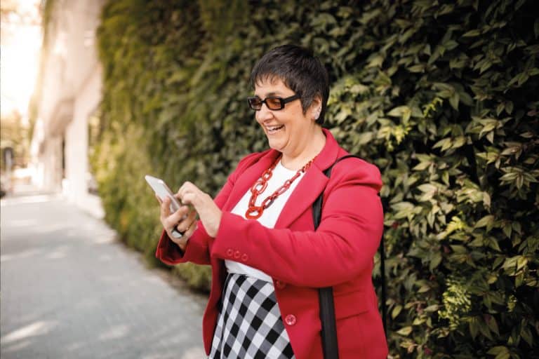 Woman over 50 with short haircut holding her phone and laughing, 12 Short Hairstyles for Plus Size Over 50