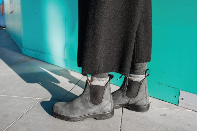Woman wearing gray leather Chelsea boots standing on pavement, How To Wear Chelsea Boots (9 Suggestions For Women)