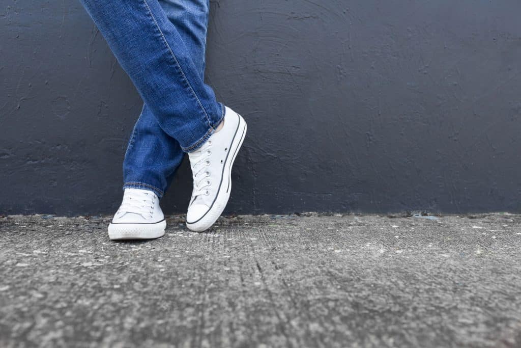 A man wearing blue denim pants and white sneakers