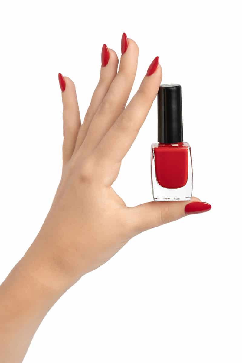 A woman holding a red nail polish in her hand
