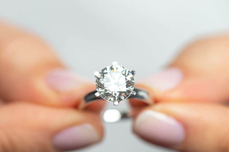 A woman holding an expensive diamond ring, Which Diamond Cut Is Least Expensive?