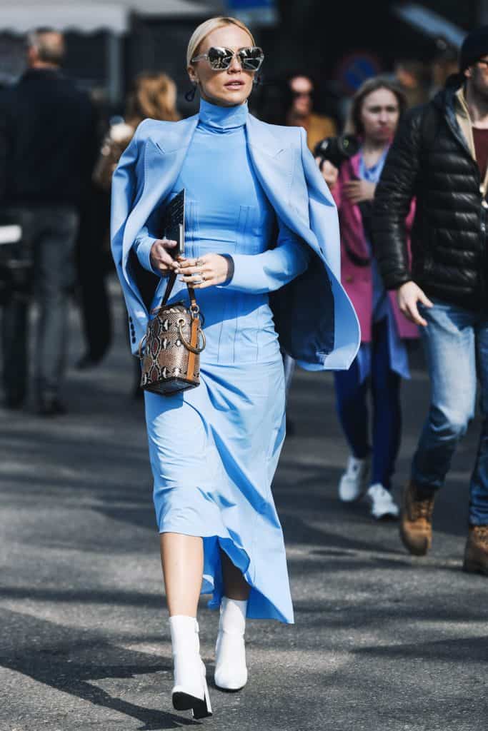 A woman wearing a blue maxi dress while holding her expensive purse