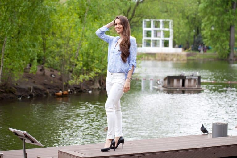 A woman wearing a blue shirt and white straight pants while standing on a platform of a river, How to Wear Straight Leg Pants