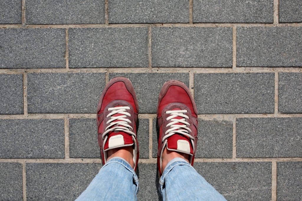 A woman wearing blue denim pants and red sneakers