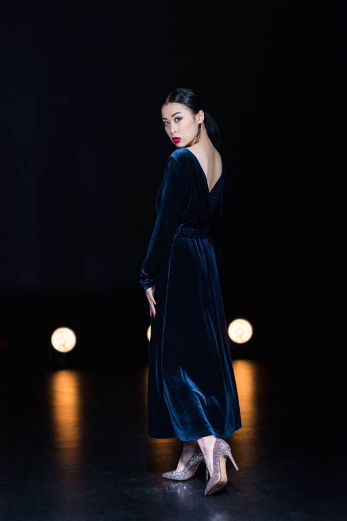 An Asian woman wearing a maxi dress while standing on a stage