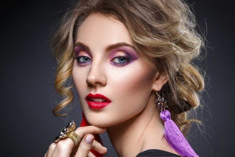 Beautiful blond young woman with bright purple makeup and tassel earrrings, What Color Lipstick Goes with Purple Eyeshadow?
