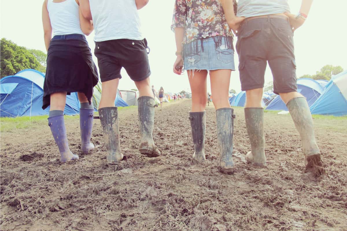 Close up of friends in Wellington boots walking to festival