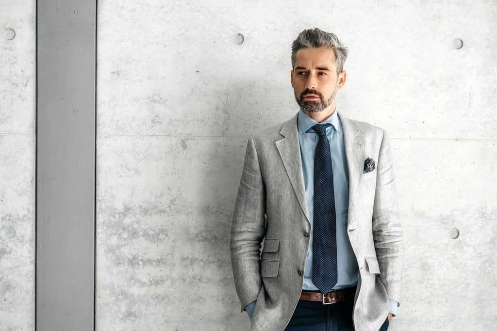 Elegant handsome bearded businessman standing in front of concrete wall