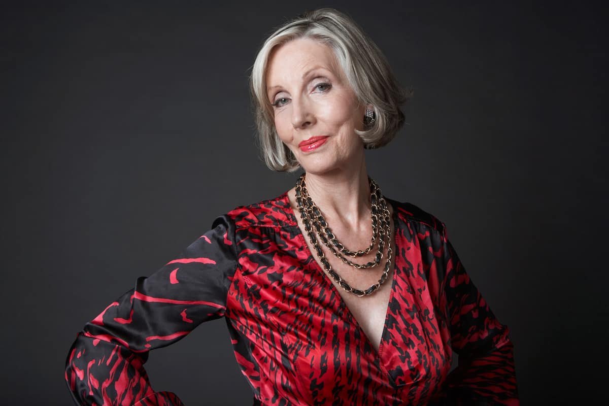 Portrait of a wealthy senior woman wearing makeup and necklace against black background