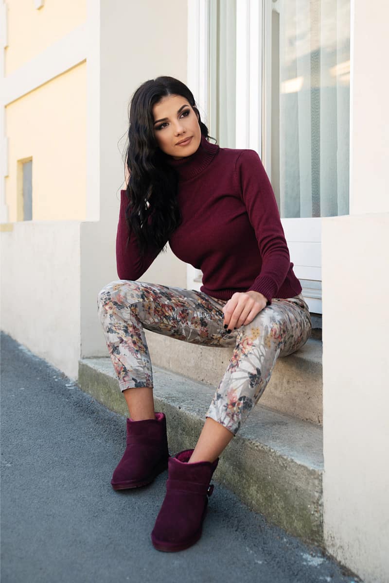 Young woman with black hair sitting outdoor in casual clothing and shearling boots