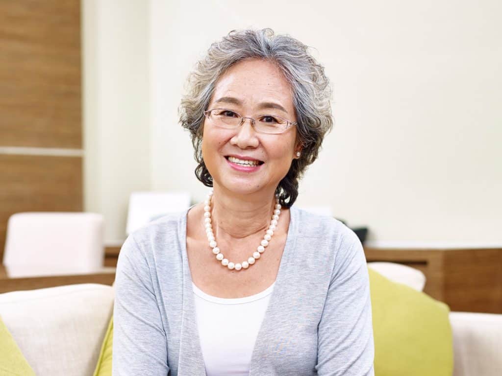 portrait of a senior asian woman with makeup, looking at camera smiling