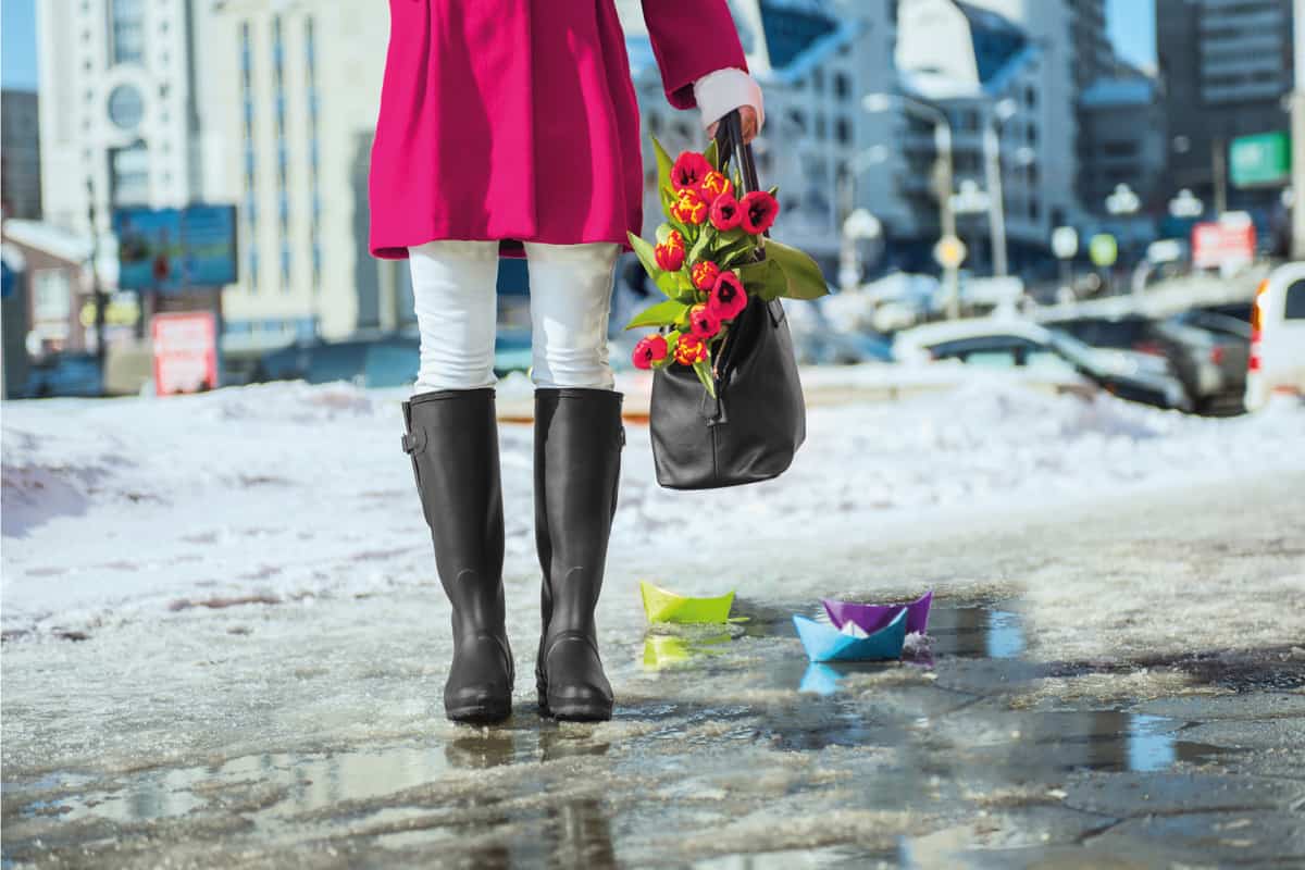 Woman carrying handbag with flowers wearing rain boots