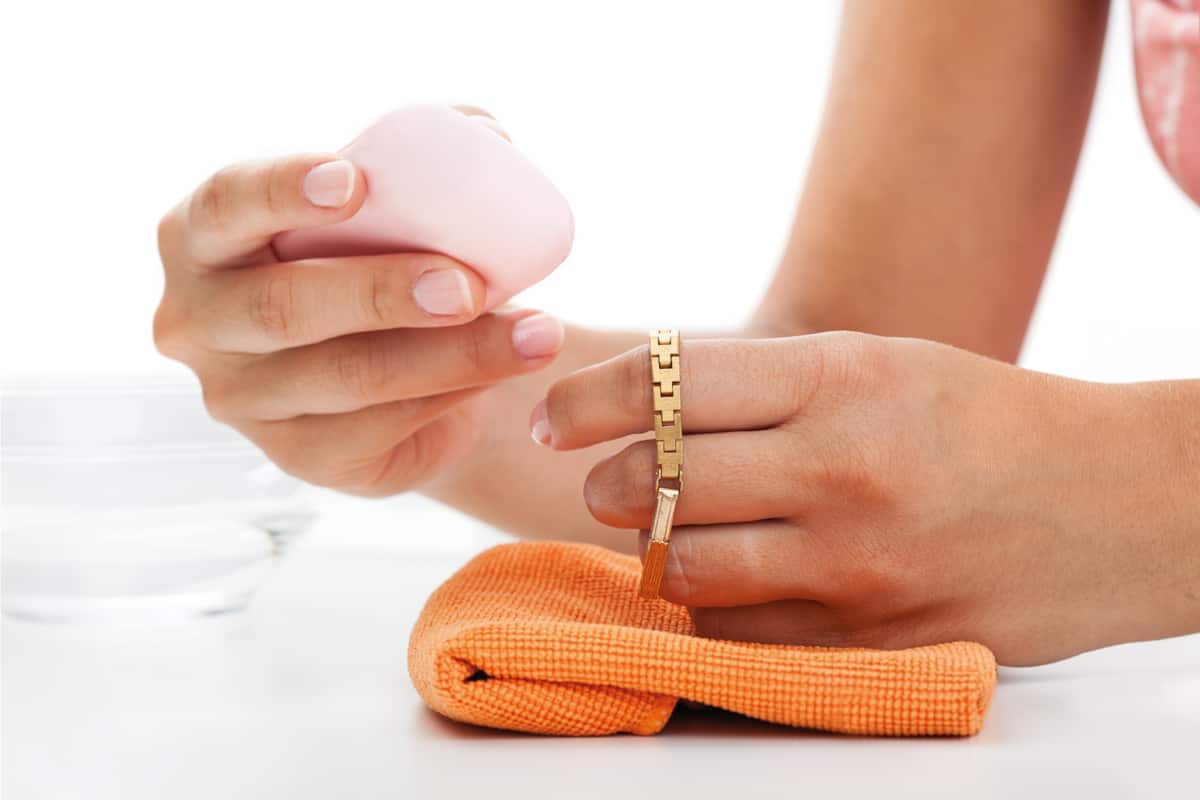 Woman cleaning a gold bracelet with mild soap