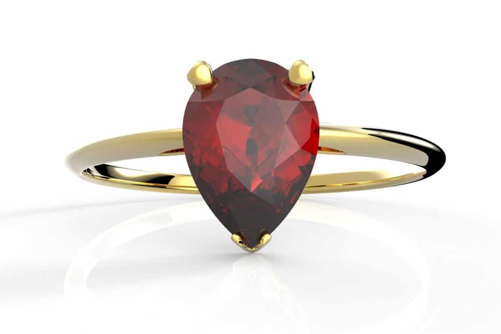 An up close and detailed photo of a golden garnet engagement ring