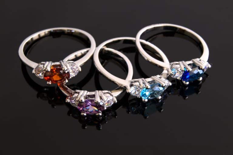 Different colored birthstone rings on a dark gray background, Which Hand Do You Wear A Birthstone Ring On?