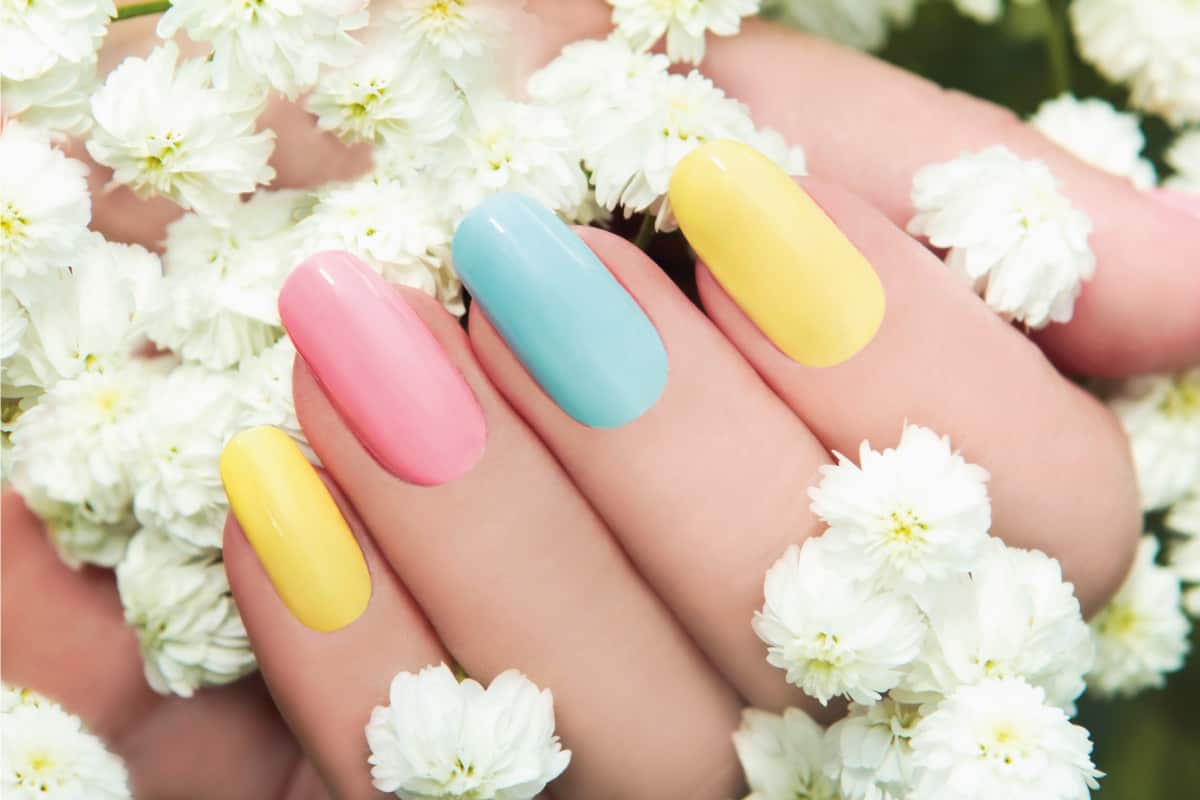 Pastel nail manicure on a woman's hand holding flowers