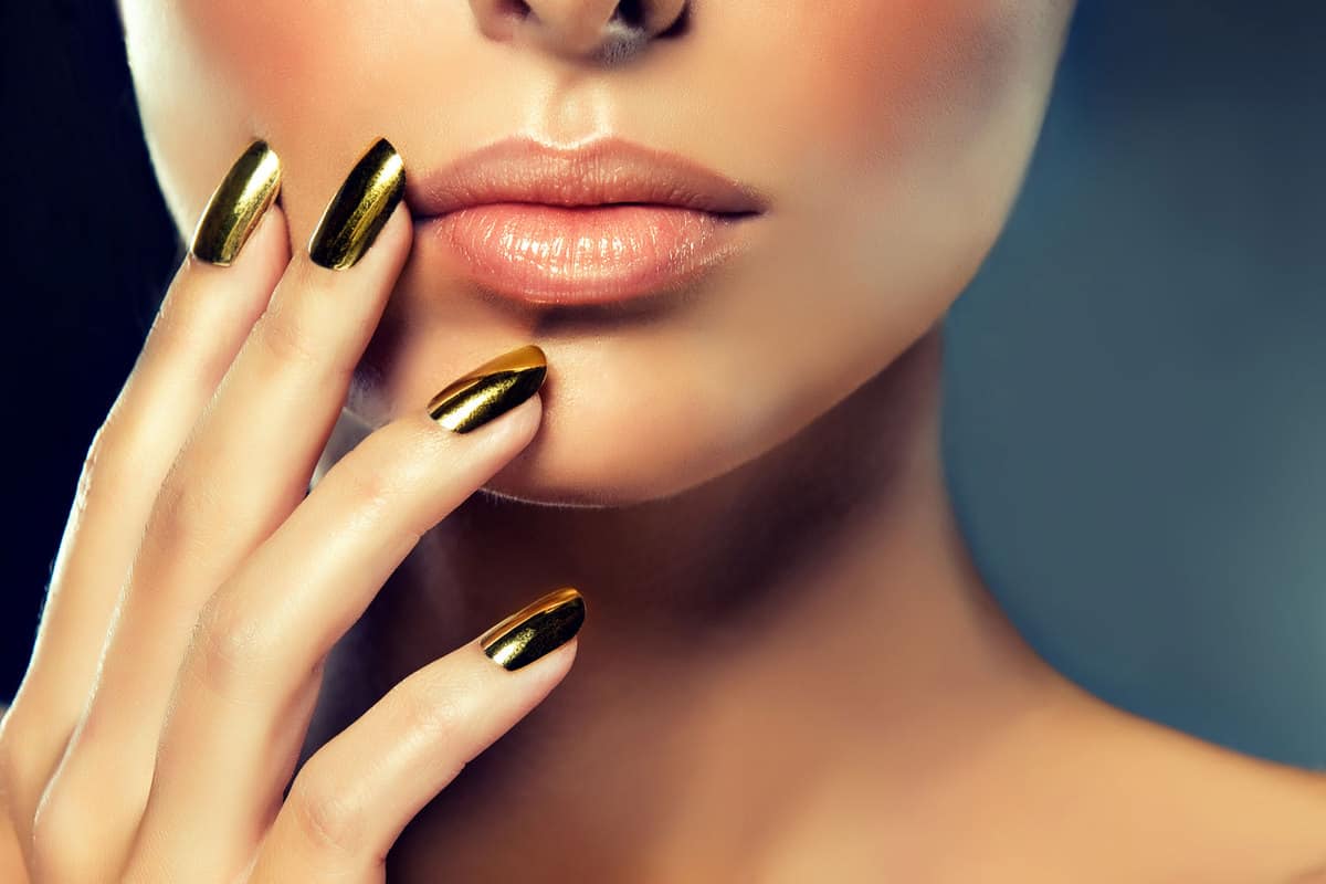 A beautiful woman showing her metallic golden acrylic nails